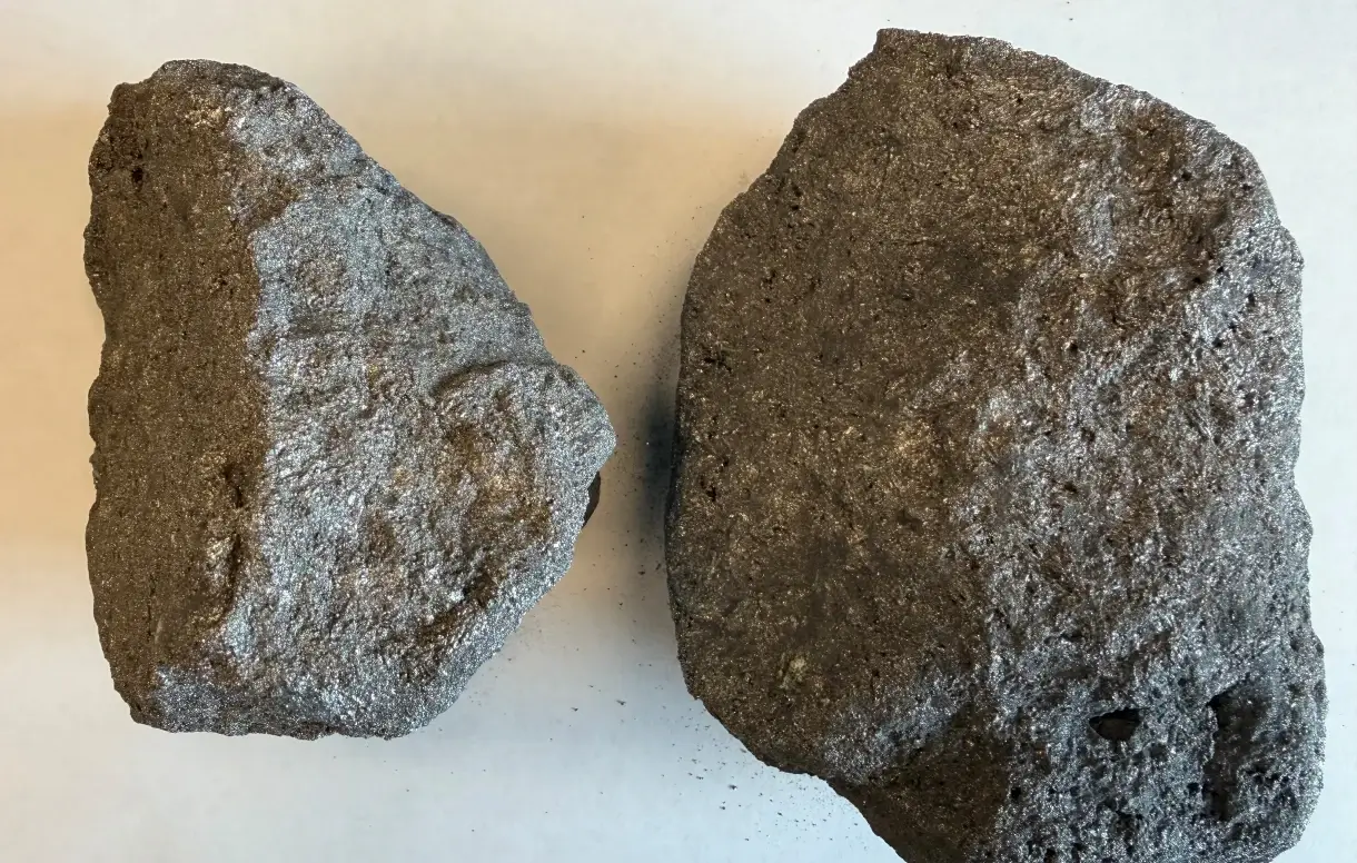 Two chunks of dark metallic vanadium-bearing slag material ready for reclamation processing