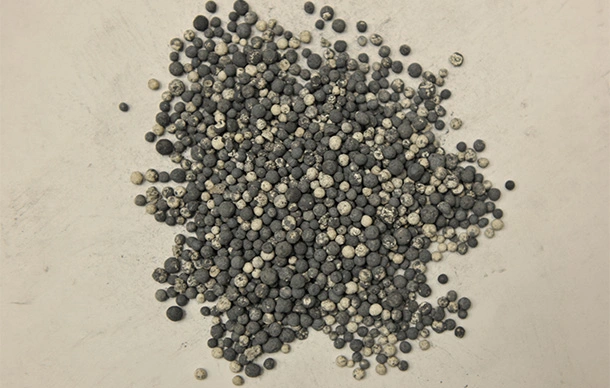 Raw palladium catalyst spheres on a table in a refining lab.