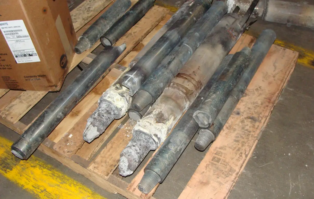 Cylindrical metal components and tubes arranged on wooden pallets with shipping documentation for scrap metal recovery