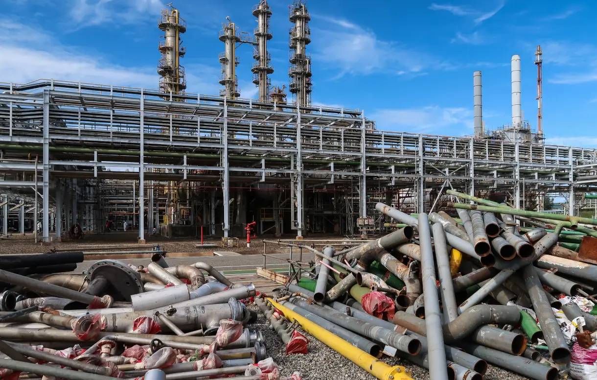 Pile of scrap metal piping staged for recycling services outside an industrial refinery